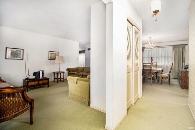 corridor with light colored carpet, a chandelier, and baseboards