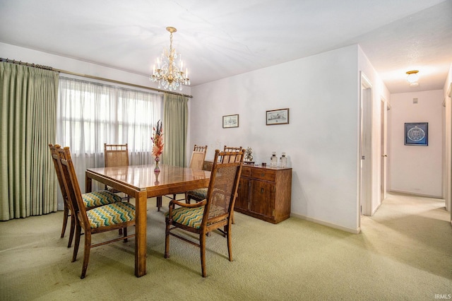 dining space featuring light colored carpet, a chandelier, and baseboards