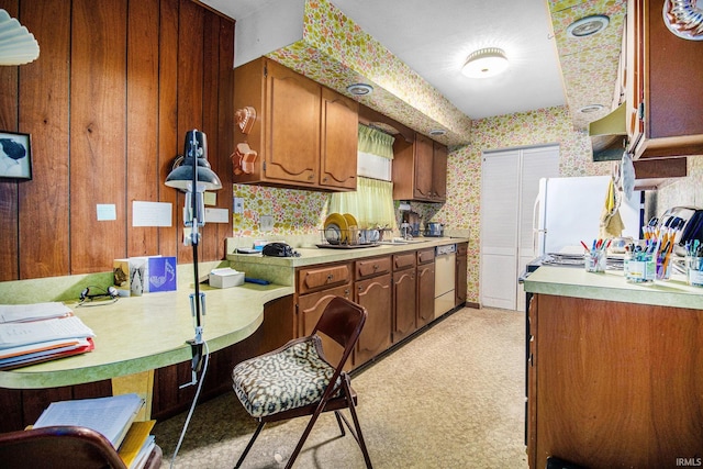 kitchen with wallpapered walls, white appliances, light countertops, brown cabinetry, and extractor fan