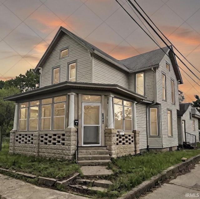 view of front of home featuring entry steps, a sunroom, and stone siding