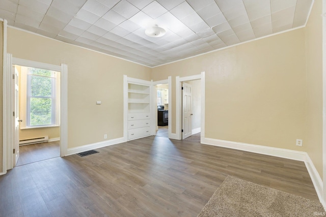 spare room with a baseboard radiator, wood finished floors, and baseboards