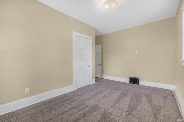 unfurnished room with a baseboard heating unit, carpet floors, and baseboards