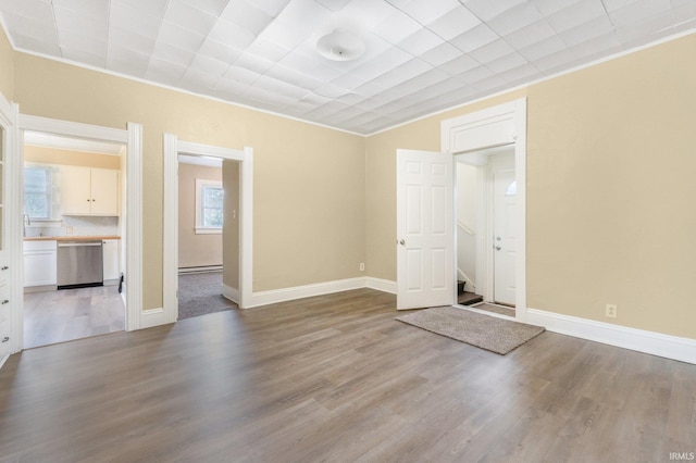 empty room featuring wood finished floors, stairs, and baseboards