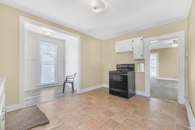 kitchen featuring black / electric stove, white cabinets, a textured ceiling, baseboards, and light countertops