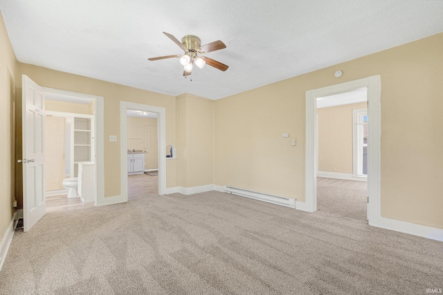 empty room featuring baseboard heating, carpet flooring, a ceiling fan, and baseboards