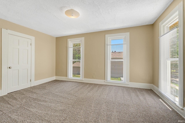 unfurnished bedroom with a textured ceiling, carpet flooring, multiple windows, and baseboards