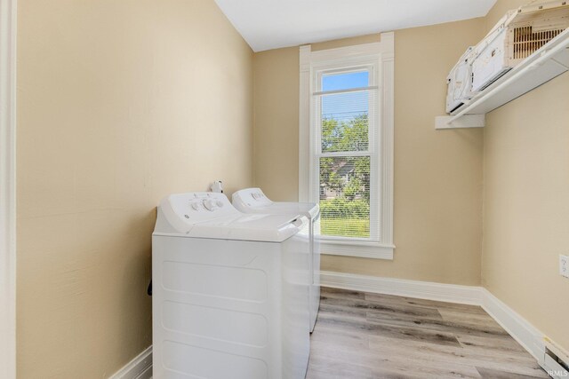 clothes washing area with washer and clothes dryer, baseboards, and wood finished floors