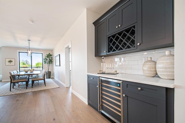 1740301W S Bend Ave, South Bend, IN 46637 - indoor dry bar with wine cooler, decorative backsplash, baseboards, light wood-style flooring, and hanging light fixtures