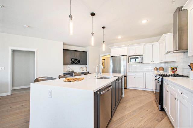 1740301W S Bend Ave, South Bend, IN 46637 - kitchen featuring appliances with stainless steel finishes, wall chimney range hood, a sink, decorative backsplash, and light wood-style floors