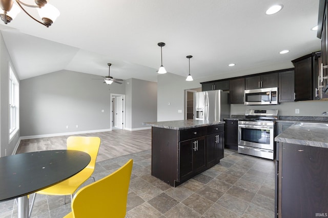kitchen with appliances with stainless steel finishes, a center island, a ceiling fan, a sink, and baseboards
