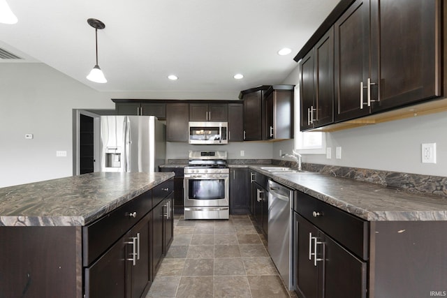 kitchen with stainless steel appliances, dark countertops, a sink, recessed lighting, and dark brown cabinets