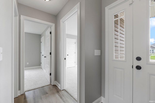 hall with light wood-type flooring and baseboards