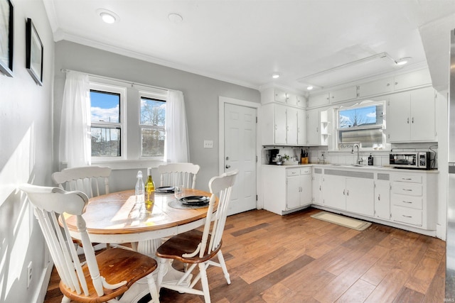 1820 Saint Marys Ave, Fort Wayne, IN 46808 - kitchen featuring a sink, crown molding, plenty of natural light, light wood-style flooring, and white cabinetry