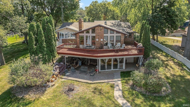 rear view of house with a wooden deck, a patio, a chimney, and brick siding