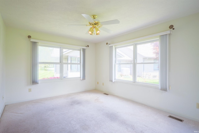 carpeted spare room featuring plenty of natural light, ceiling fan, and baseboards