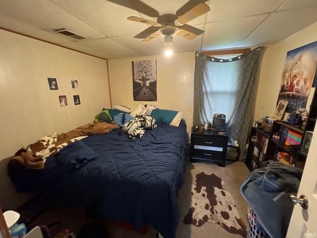 bedroom with a drop ceiling, carpet, and ceiling fan