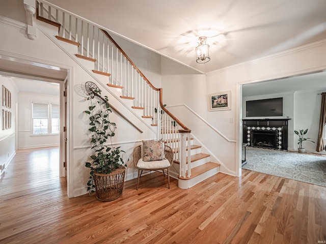 727 Mulberry St, Mount Vernon, IN 47620 - stairway with wood finished floors, baseboards, a fireplace, ornamental molding, and a chandelier