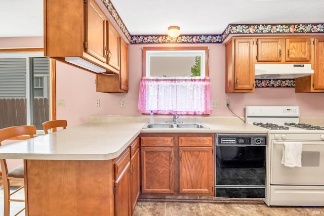 1723 Central St, Lafayette, IN 47905 - kitchen with under cabinet range hood, black dishwasher, white range with gas cooktop, a sink, and a kitchen bar