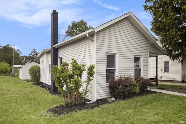 view of side of home with a chimney and a lawn
