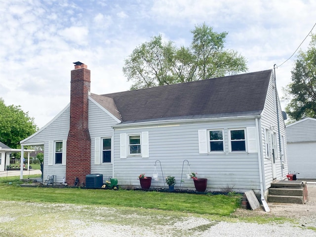 6913 E Jackson St, Muncie, IN 47303 - back of house featuring central AC, a chimney, an outdoor structure, and roof with shingles