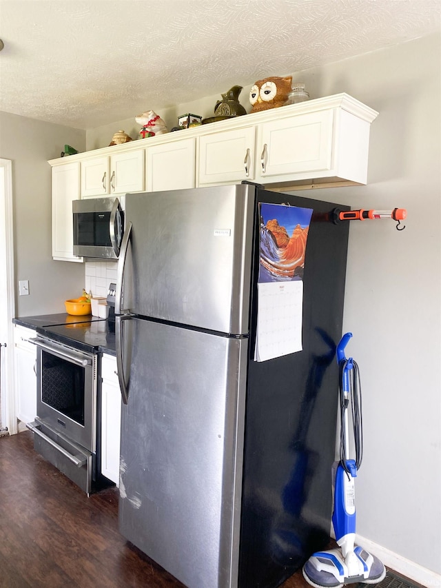 6913 E Jackson St, Muncie, IN 47303 - kitchen with appliances with stainless steel finishes, dark wood finished floors, white cabinets, dark countertops, and a textured ceiling