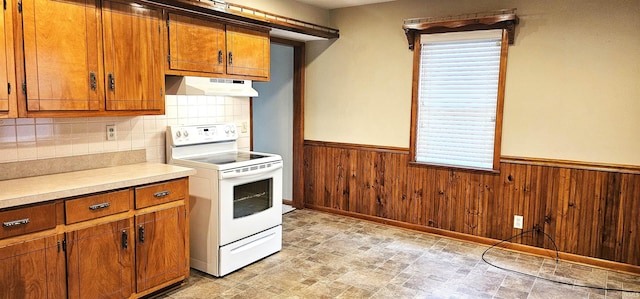 318 W Jefferson St, Chandler, IN 47610 - kitchen featuring white electric stove, under cabinet range hood, brown cabinetry, a wainscoted wall, and light countertops
