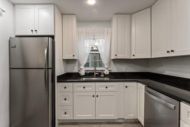 kitchen with appliances with stainless steel finishes, a sink, and white cabinets