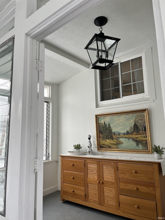 bar area with a chandelier, a textured ceiling, and baseboards
