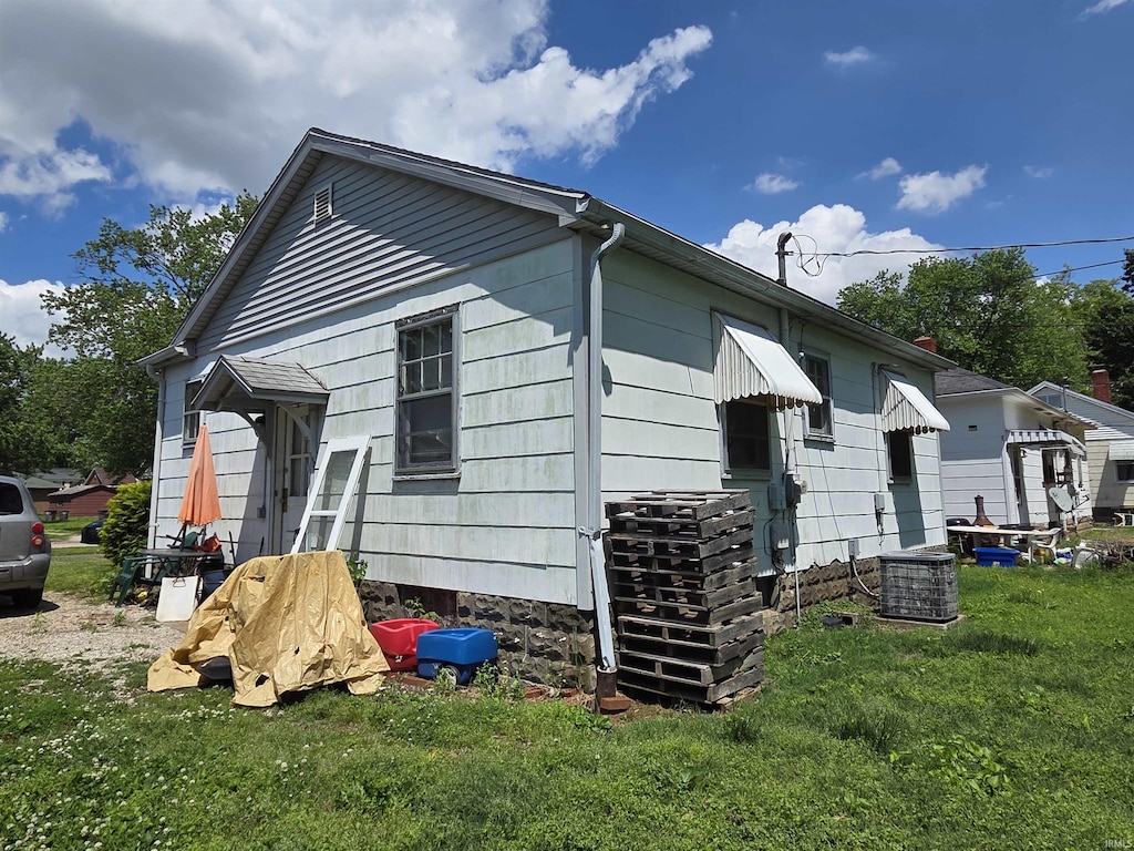 back of house with a yard and central AC