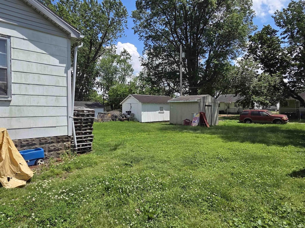 view of green lawn featuring a storage shed and an outbuilding