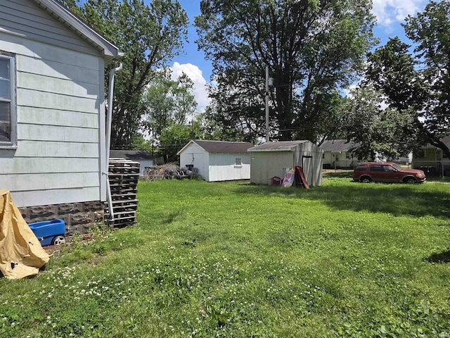 view of green lawn featuring a storage shed and an outbuilding