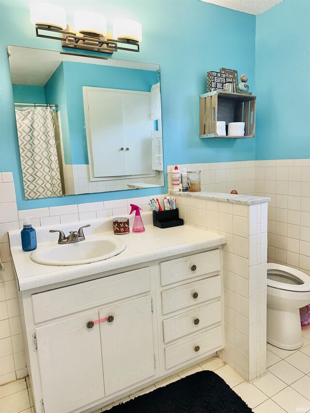 2912 W Twickingham Dr, Muncie, IN 47304 - full bath with tile patterned floors, tile walls, vanity, toilet, and wainscoting