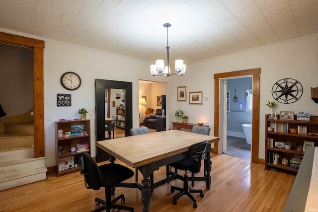 dining room with light wood-style flooring, a chandelier, stairs, and ornamental molding