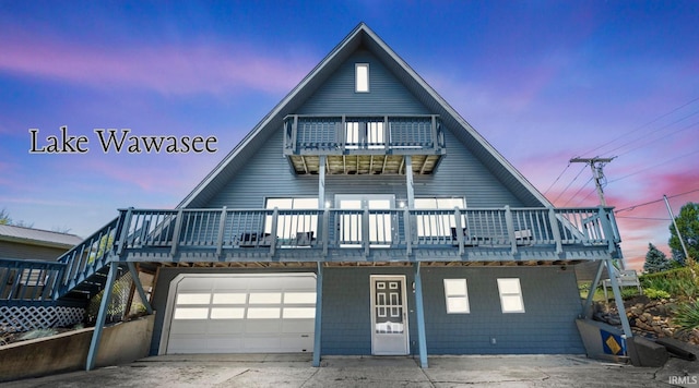 11381 NE Wawasee Dr, Syracuse, IN 46567 - view of front of house featuring a balcony, a garage, driveway, and a wooden deck
