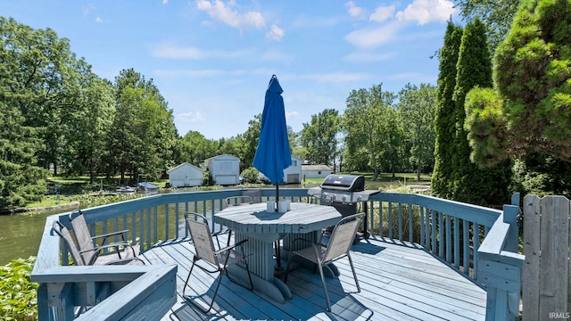 11381 NE Wawasee Dr, Syracuse, IN 46567 - wooden deck with outdoor dining area, view of scattered trees, and a water view