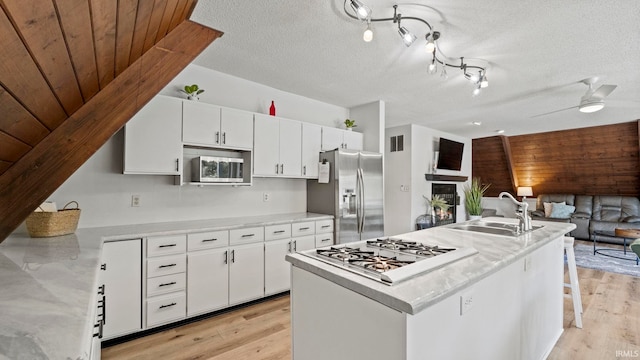 11381 NE Wawasee Dr, Syracuse, IN 46567 - kitchen featuring stainless steel appliances, a sink, light wood-style floors, white cabinets, and open floor plan