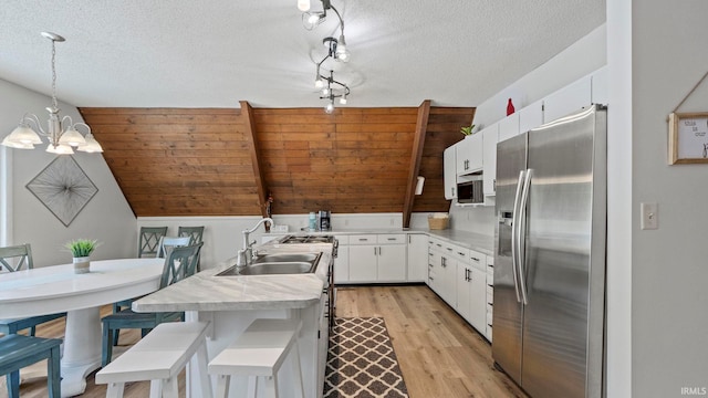 11381 NE Wawasee Dr, Syracuse, IN 46567 - kitchen featuring appliances with stainless steel finishes, a sink, a chandelier, white cabinets, and light countertops