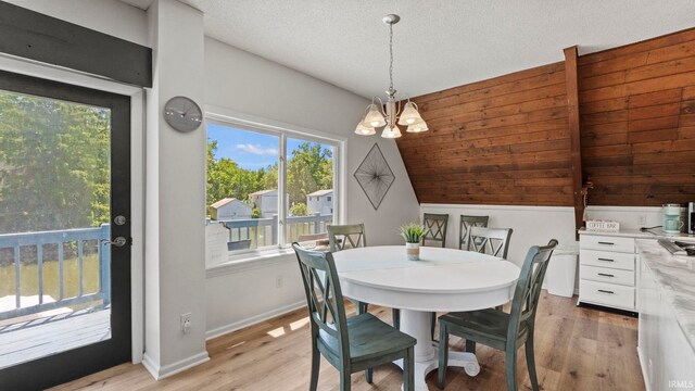 11381 NE Wawasee Dr, Syracuse, IN 46567 - dining space featuring a chandelier, light wood finished floors, lofted ceiling, and baseboards