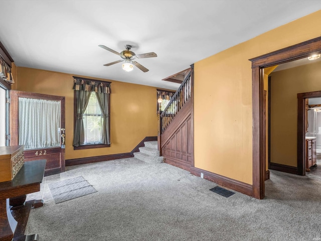 422 E Washingtion St, Oakland City, IN 47660 - unfurnished living room featuring carpet flooring, baseboards, stairs, and ceiling fan