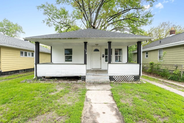 view of front of home featuring a front lawn, covered porch, and roof with shingles