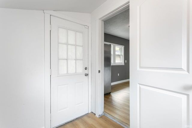 doorway with light wood-style floors and baseboards