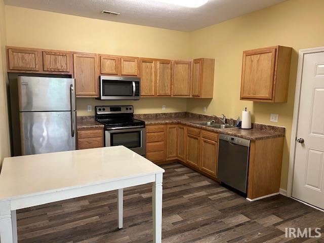 1221 N Lindbergh Dr, Bloomington, IN 47404 - kitchen with appliances with stainless steel finishes, a sink, dark wood-style floors, and dark countertops
