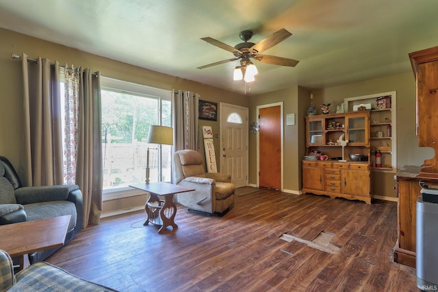 living room with dark wood-style floors, ceiling fan, and baseboards