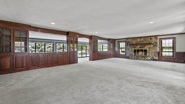 unfurnished living room with carpet floors, plenty of natural light, a fireplace, recessed lighting, and a textured ceiling