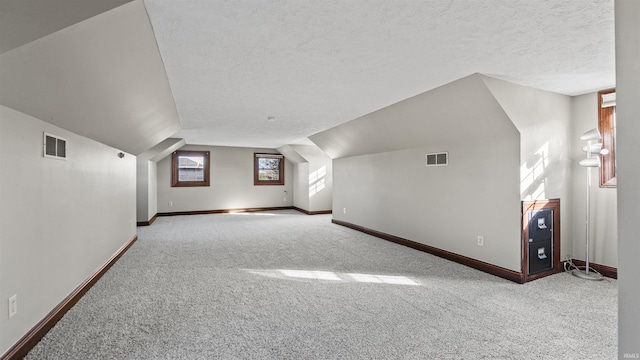 bonus room featuring carpet floors, baseboards, vaulted ceiling, and a textured ceiling