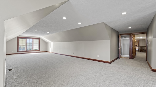 additional living space with carpet floors, baseboards, a textured ceiling, lofted ceiling, and recessed lighting