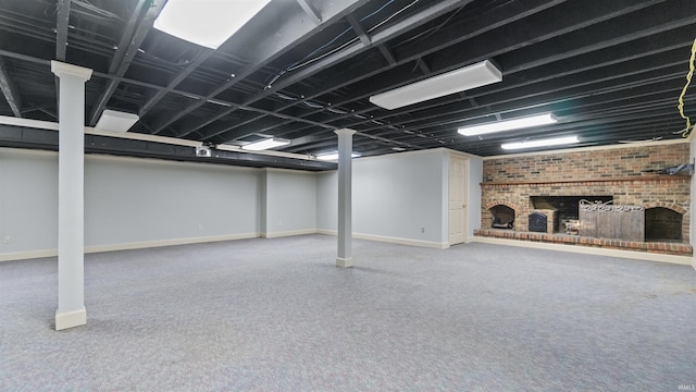 finished basement featuring a brick fireplace, carpet flooring, and baseboards