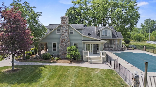 rear view of house with central air condition unit, a deck, a chimney, a patio area, and roof with shingles