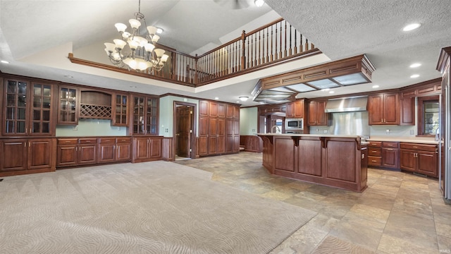 kitchen featuring stainless steel microwave, wall chimney range hood, a chandelier, a breakfast bar, and recessed lighting
