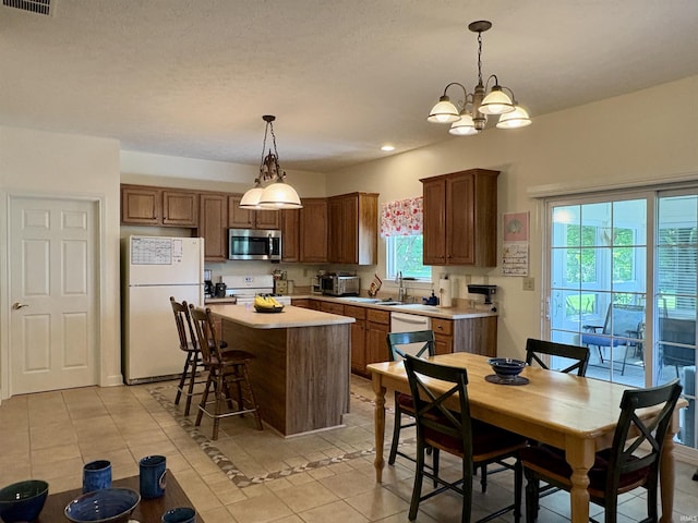 1804 Canyon Creek Dr, Lafayette, IN 47909 - kitchen featuring white appliances, light tile patterned flooring, light countertops, a kitchen island, and decorative light fixtures